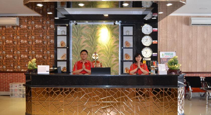 a woman standing in front of a counter with a large mirror, Puncak Budget Hotel in Bangka