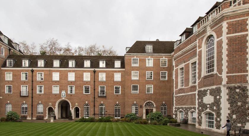 a large brick building with a clock on the front of it, Goodenough College – University Residence in London