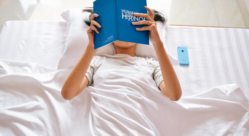 a woman laying on a bed holding a cell phone, Ha Nhi Hotel in Ninh Bình