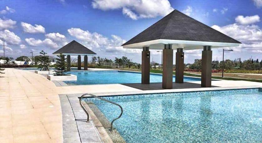 a large swimming pool with a large blue umbrella, Hannah's Place at Wind Residences in Tagaytay