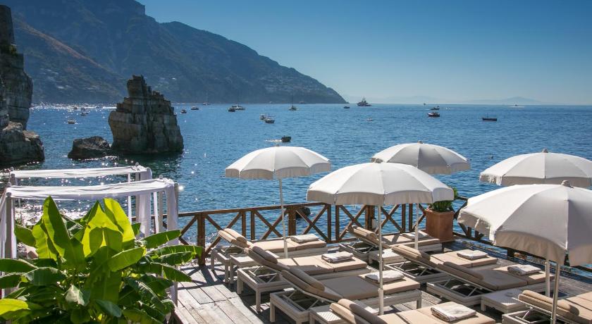 a beach area with umbrellas, chairs, and tables, Hotel Le Agavi in Positano