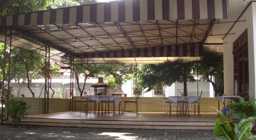 a patio area with a table, chairs and umbrellas, Hotel Wisma Sakinah in Yogyakarta