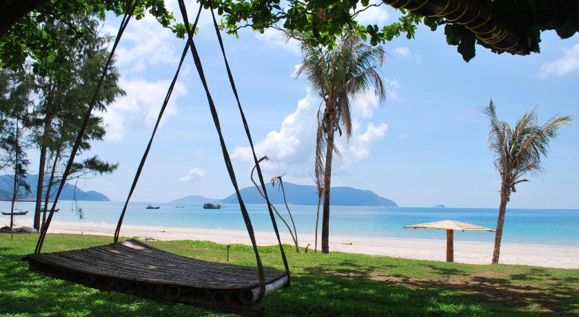 a wooden bench sitting on top of a sandy beach, Con Dao Resort in Côn Đảo Islands