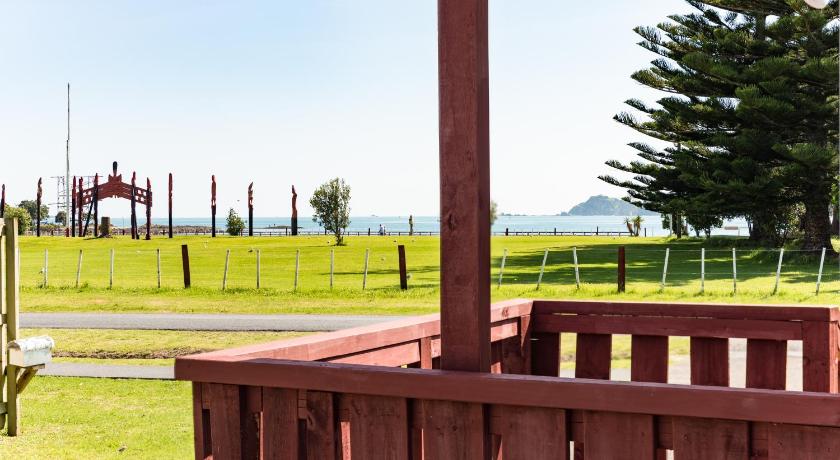 a wooden bench sitting on top of a lush green field, Waitangi Beach Unit A in Bay of Islands