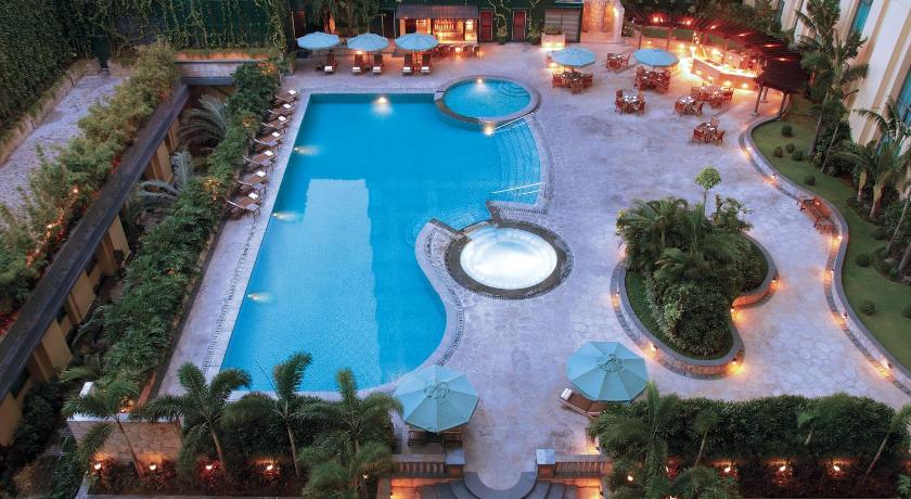 a patio area with a pool, chairs, and tables, New Coast Hotel Manila in Manila