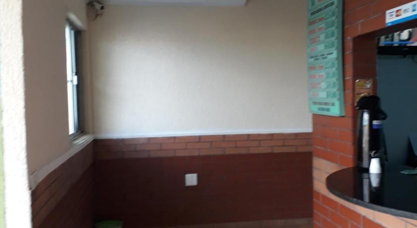 a room with a television and a wall with a brick wall, Hotel tenda 1 in Guarulhos