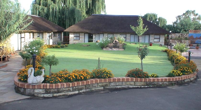 a garden with a tree and a house, Black Swan Guesthouse in Maseru