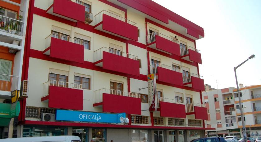 a red building with a bunch of windows on top of it, Aparthotel Avenida in Mindelo