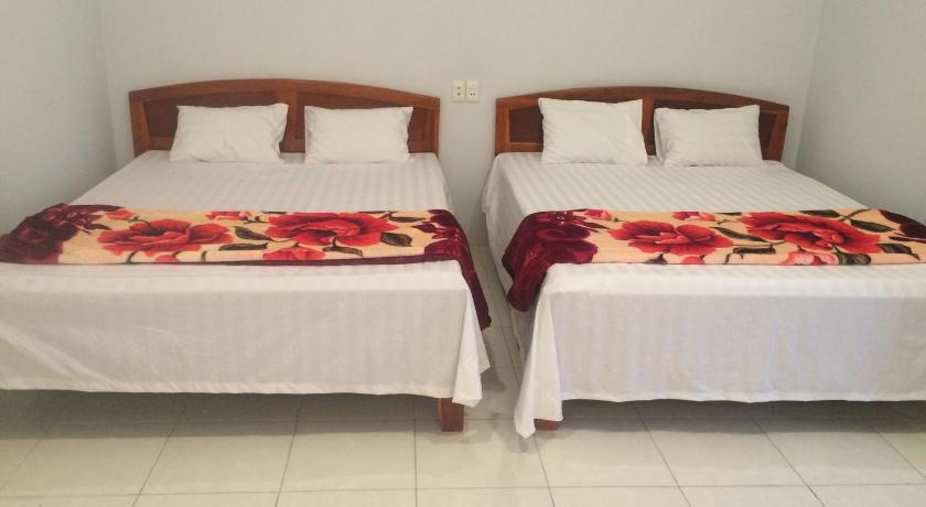 two beds in a room with white sheets and pillows, Y Bon in Phan Thiet