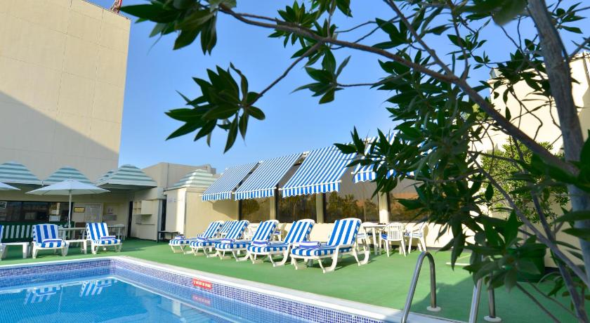a beach with a pool, chairs and a pool table, Ramada by Wyndham Bahrain in Manama