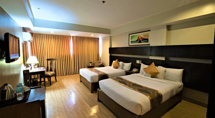 a hotel room with two beds and a television, Pinnacle Hotel and Suites in Davao City