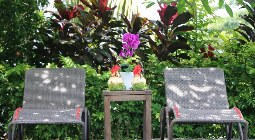 two chairs and a table in a garden area, Puri Bunga Beach Cottages Hotel in Lombok