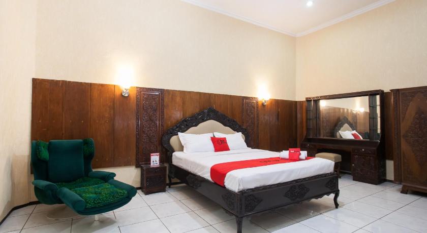 a hotel room with a bed, chair, and nightstand, RedDoorz  near Brawijaya University in Malang