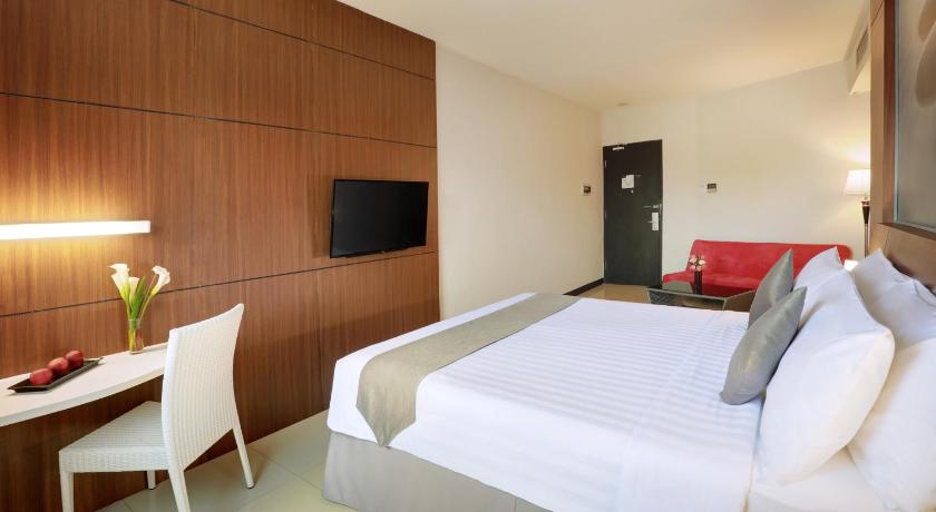 a hotel room with a bed, chair, table and a lamp, Hotel Neo Palma - Palangkaraya by ASTON in Palangkaraya