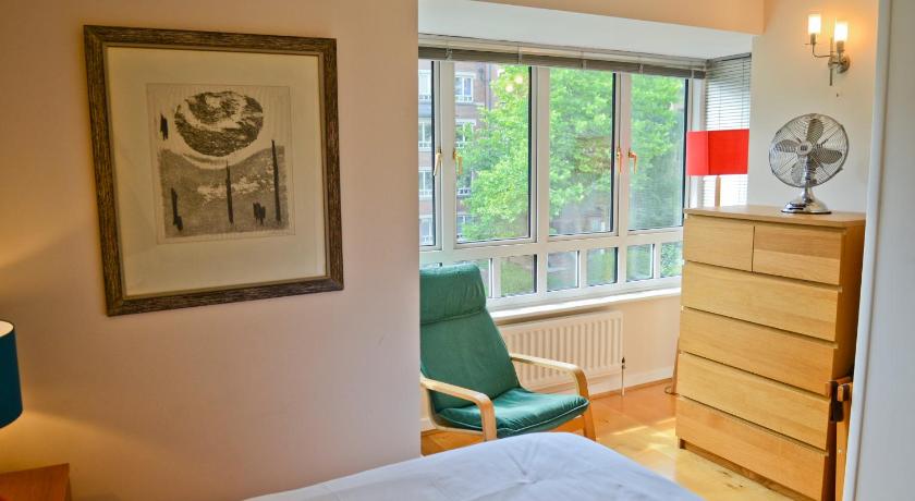 a bedroom with a bed, chair, lamp and window, Florey Lodge in London