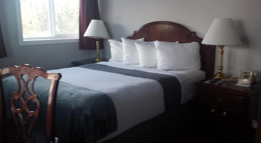 a bed with a white comforter next to a window, Beluga Lake Lodge in Homer (AK)