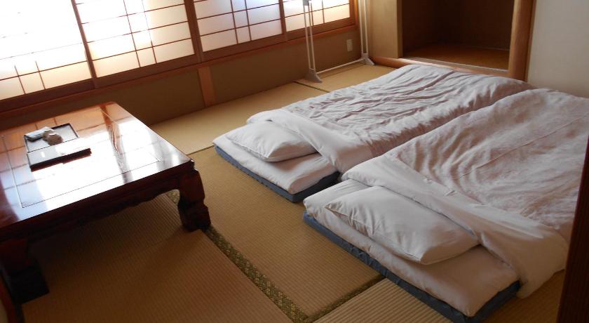 a bed room with two beds and a table, New Central Hotel Katsuta in Hitachinaka