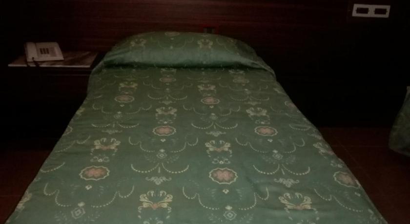 a neatly made bed in a small room, Hotel Leonardo Da Vinci in Sassari