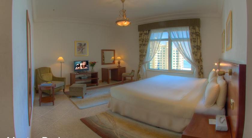 a bedroom with a bed, chair, lamp and window, Royal Club Palm Jumeirah in Dubai