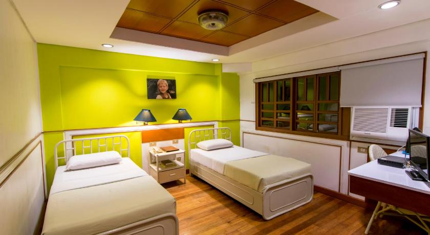 a hotel room with two beds and two lamps, The Manor Hotel Davao in Davao City