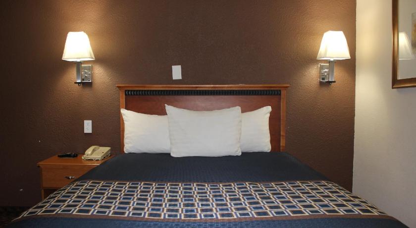 a bedroom with a bed and a lamp, Travel Inn Omaha in Omaha (NE)