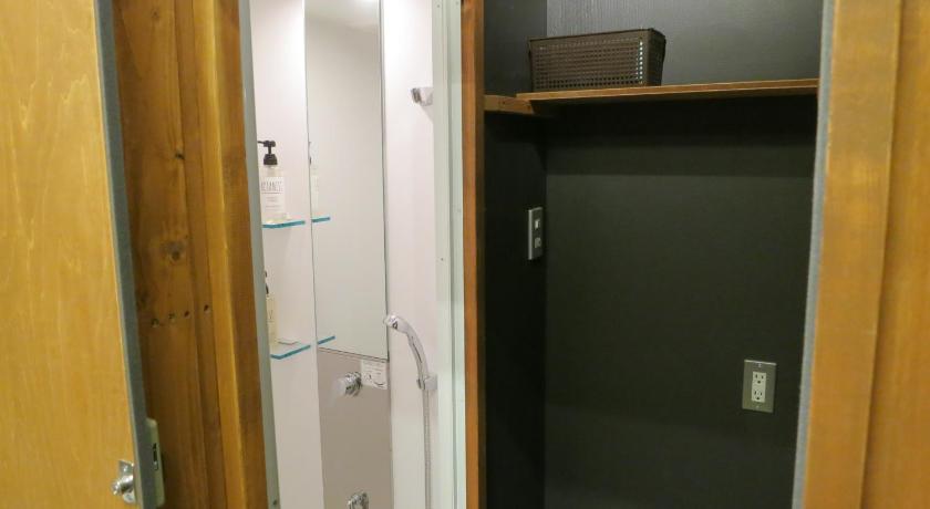 a bathroom with a door open and a shower stall, No Borders Hostel in Tokyo