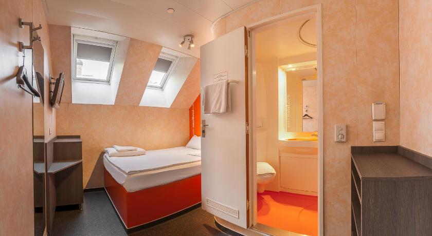 a hotel room with a bed and a dresser, easyHotel Budapest Oktogon in Budapest