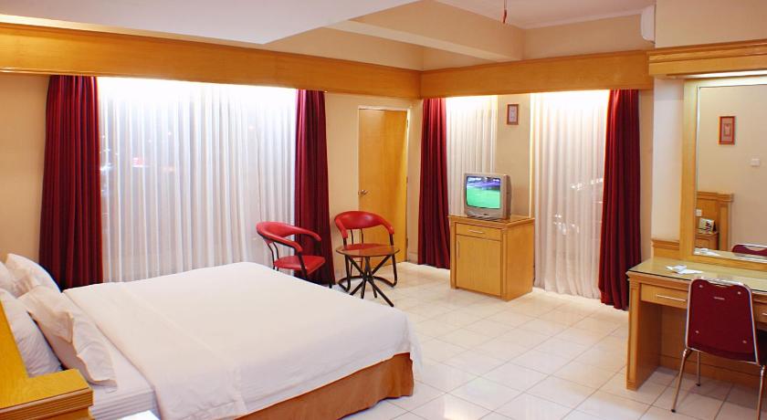 a hotel room with a bed, chair and a television, Hotel Hangtuah in Padang