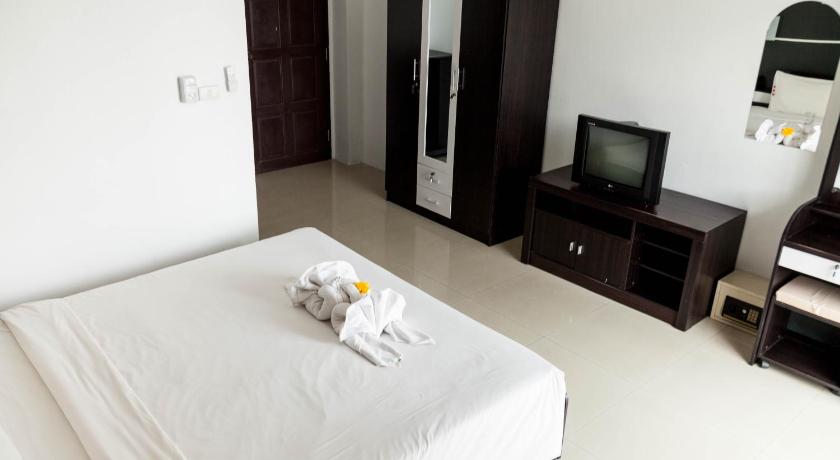 a white bed sitting in a room next to a tv, Happy Fish Guesthouse in Phuket