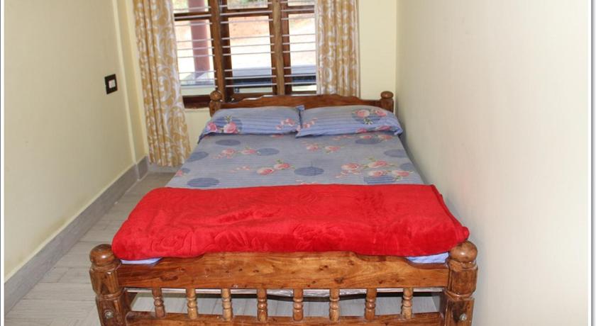 a bed with a red bedspread and pillows in a room, Lahari Welcomes You in Coorg