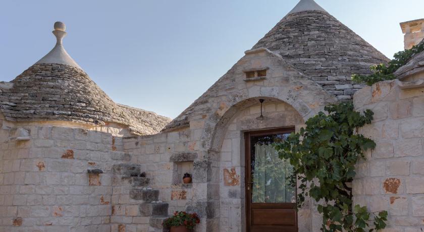 an old brick building with a clock on the front of it, Almapetra Trulli Resort in Locorotondo