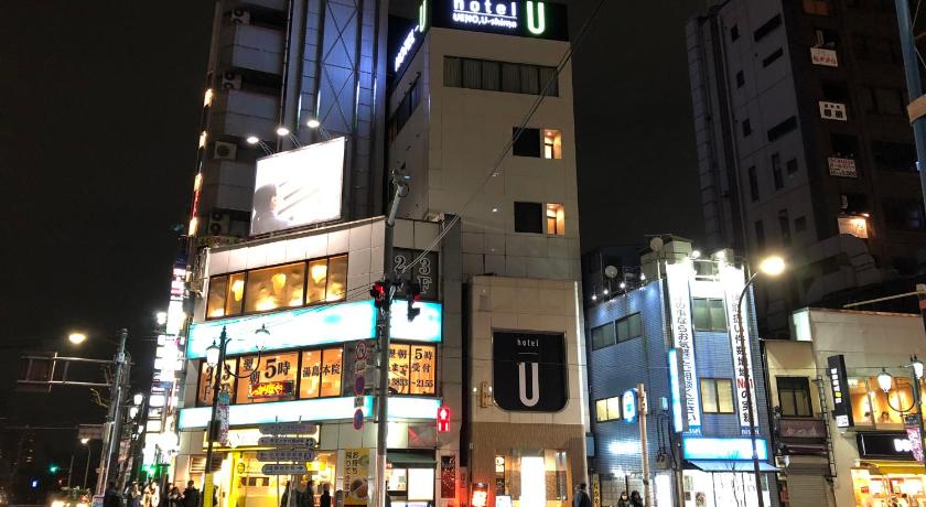 a city street at night with tall buildings, Hotel U in Tokyo