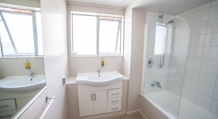 a bathroom with a sink, tub, and shower, City Central Motel Apartments in Christchurch