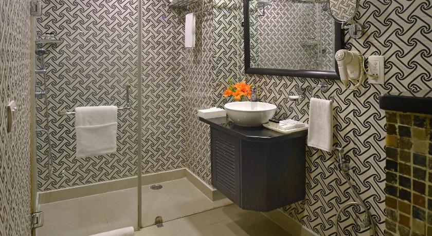 a bathroom with a toilet, sink, and mirror, Taurus Sarovar Portico in New Delhi and NCR