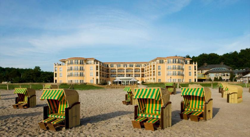 a row of wooden benches in front of a beach, Hotel Gran BelVeder in Scharbeutz
