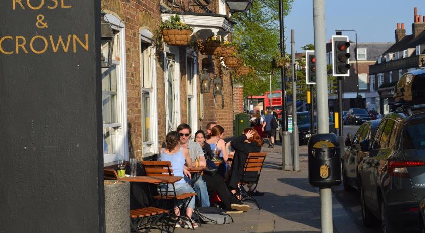 people sitting on a bench in front of a building, Wimbledon Views in London