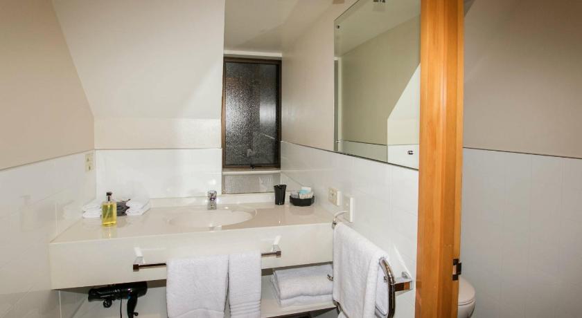 a bathroom with a sink, toilet and mirror, Allan Court Motel in Dunedin