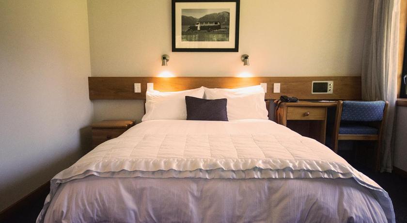 a bed in a bedroom with a white bedspread, Alpine Lodge in Saint Arnaud