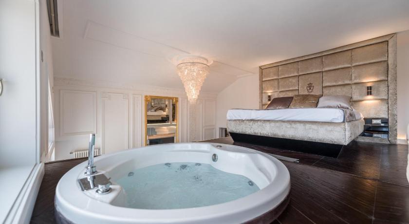 a bath room with a tub and a bed, Enzo Capo Luxury Suites in Budapest