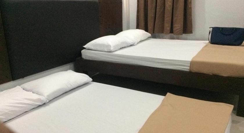a hotel room with two beds and two nightstands, WestCourt Inn in Ilocos Sur