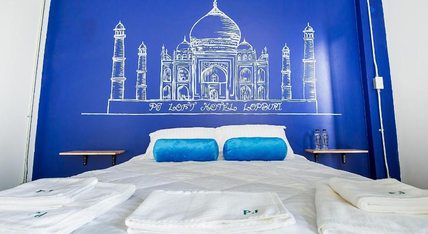 a bed with a blue and white bedspread and a blue and white bed, PJ Loft Hotel in Lopburi