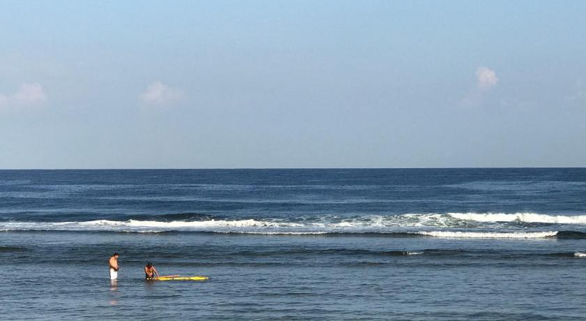 a person riding a surfboard on top of a wave in the ocean, Rooftop Family Room in PATAR - Beachfront with Pool in Bolinao