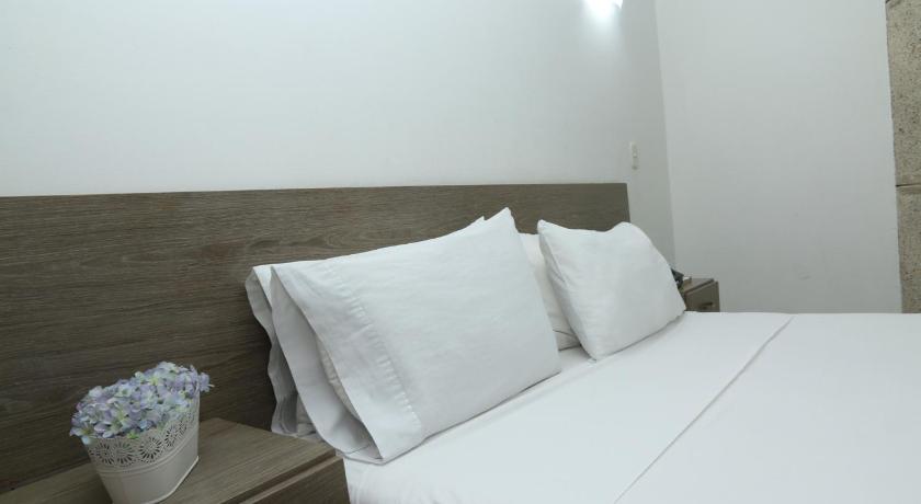 a white bed with a white pillow on top of it, Hotel Yivinaca in Barranquilla