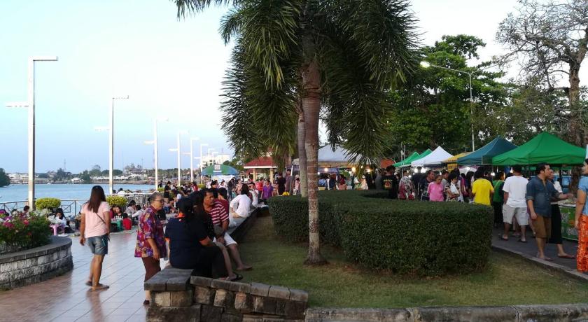 a crowd of people walking down a sidewalk next to palm trees, Phongkaew Hotel in Surat Thani