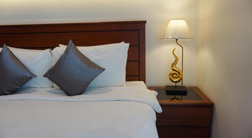 a bed with a white comforter and pillows, Lanna Tree Boutique Hotel in Chiang Mai