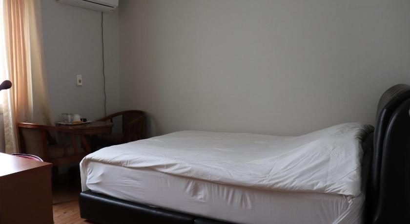 a bed with a white comforter and pillows, Orasung Motel in Jeju