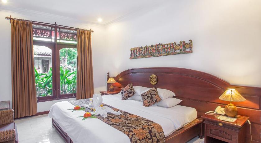 a bedroom with a large bed and a large window, Tamukami Hotel in Bali