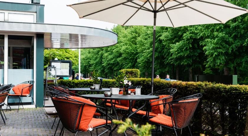 a dining area with a table and chairs with umbrellas, Hotel 't Paviljoen in Rhenen