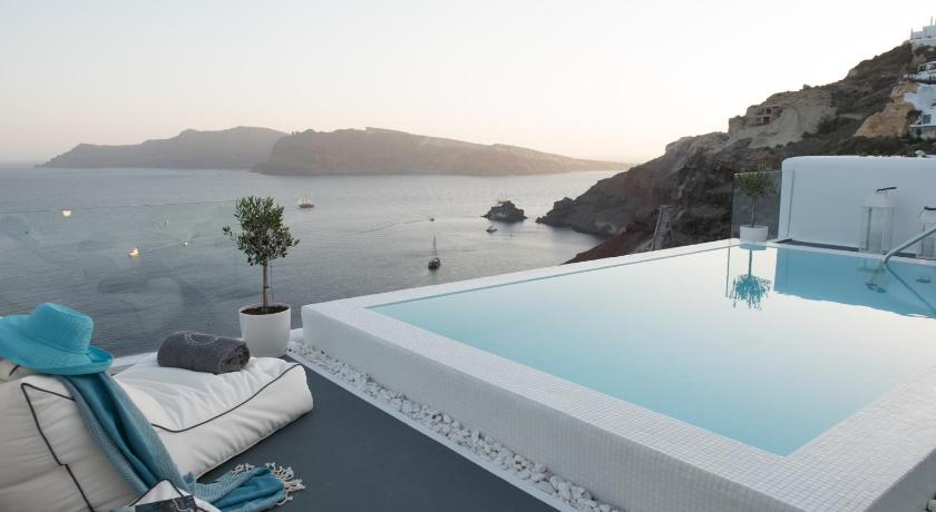 a large white boat sitting on top of a body of water, La Perla Villas - Adults Only in Santorini