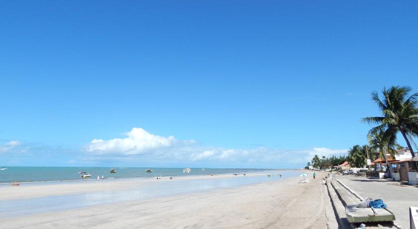 a beach with a beach chair on the beach next to the ocean, Suites Igogaram in Maragogi